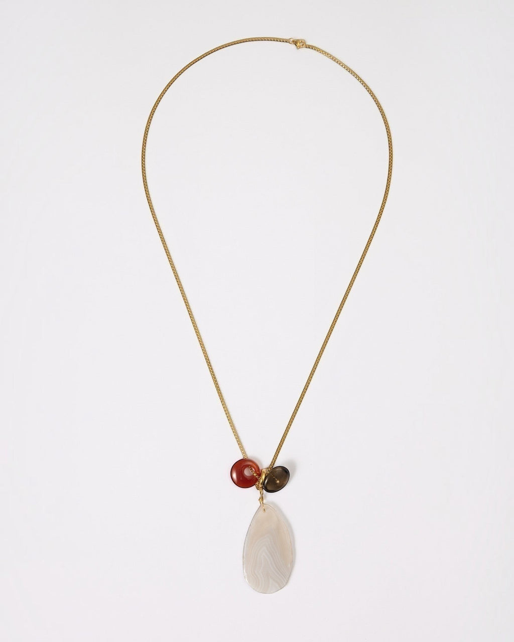 Elsita Jewelry Glacier Day necklace featuring a white agate slice, red agate ring, and smoky quartz on a gold chain.