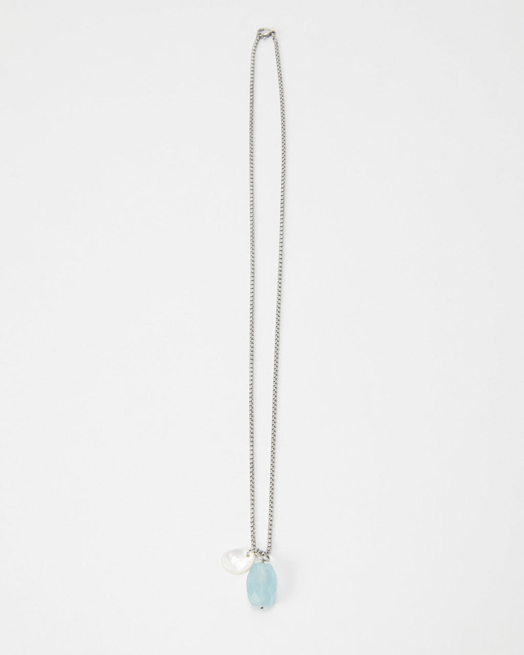 Elsita Jewelry Azul necklace featuring a light blue faceted gemstone and a small white pearl charm on a silver chain