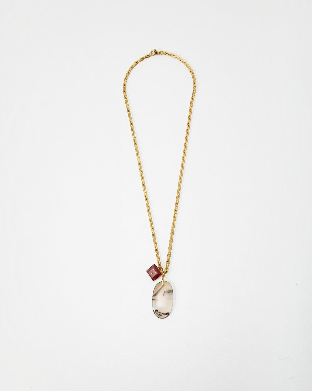 Elsita Jewelry Calligraphy necklace featuring a gold chain with a large oval agate pendant and a small red cube charm