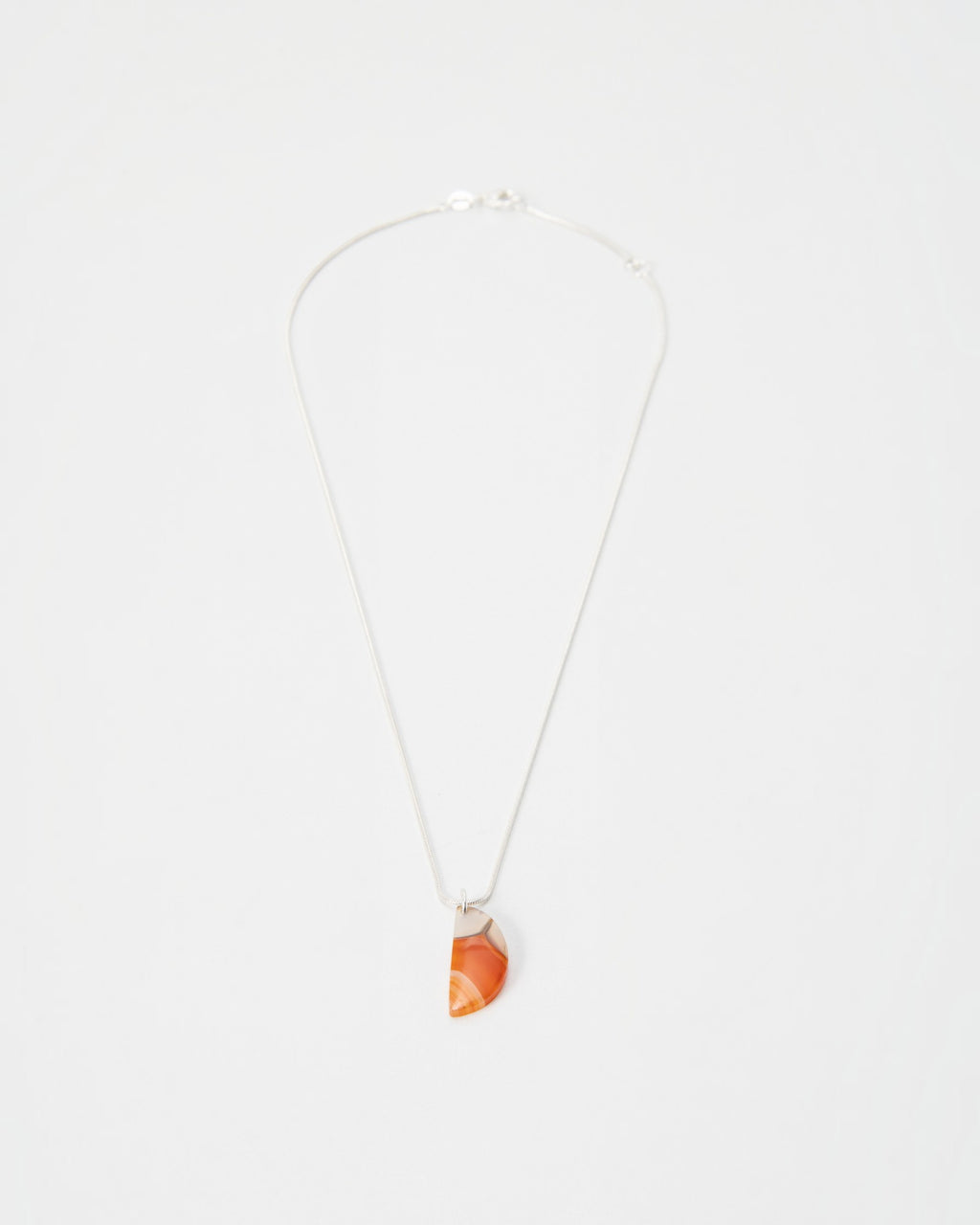 Elsita Jewelry Citrus I necklace featuring a semi-circular orange agate pendant on a delicate silver chain