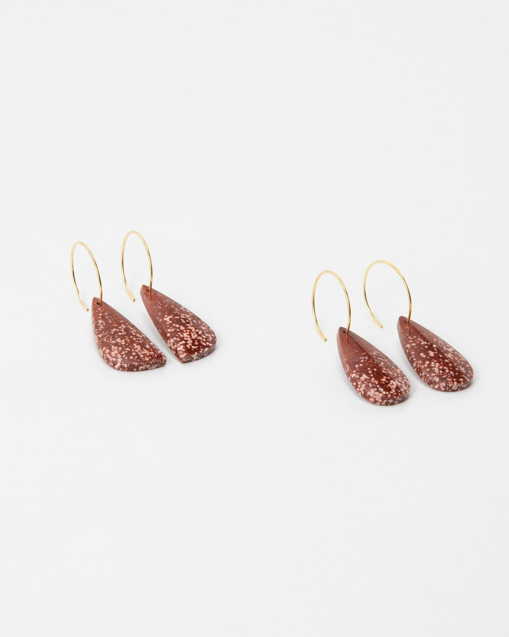 Elsita Jewelry Coral earrings featuring teardrop-shaped speckled terracotta clay charms on thin gold hoop wires.