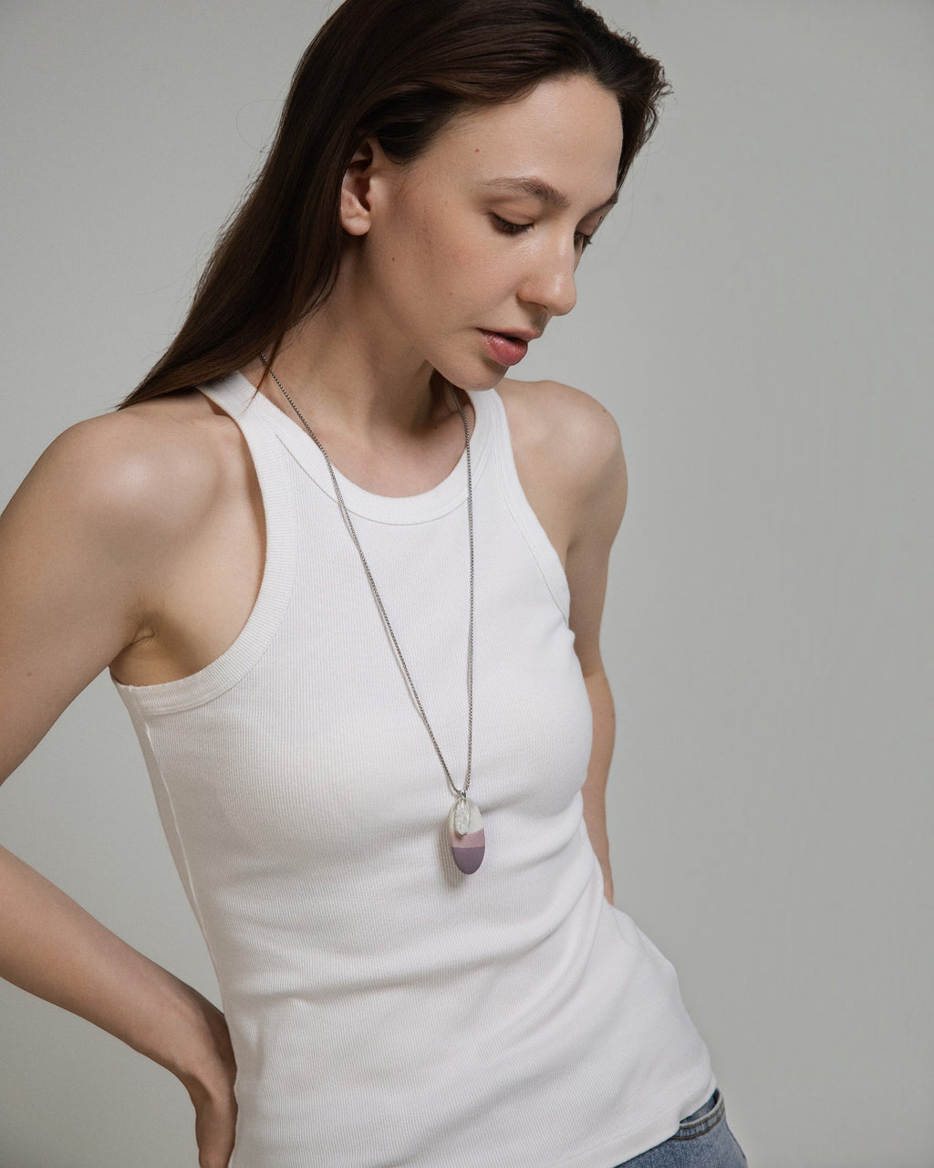 Elsita Jewelry Mauve I necklace featuring a Hyacinth Jasper pendant on a stainless steel chain worn by a woman.