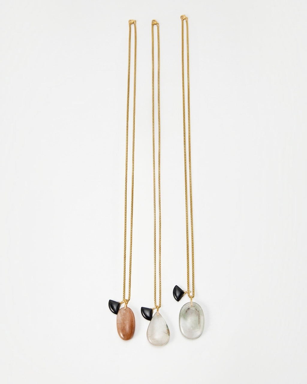 Elsita Jewelry Mist I necklaces featuring gold chains with dangling smooth stone pendants and small black accents