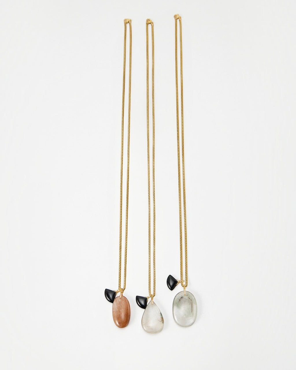 Elsita Jewelry Mist II necklaces featuring gold chains with oval stone pendants and small black accents