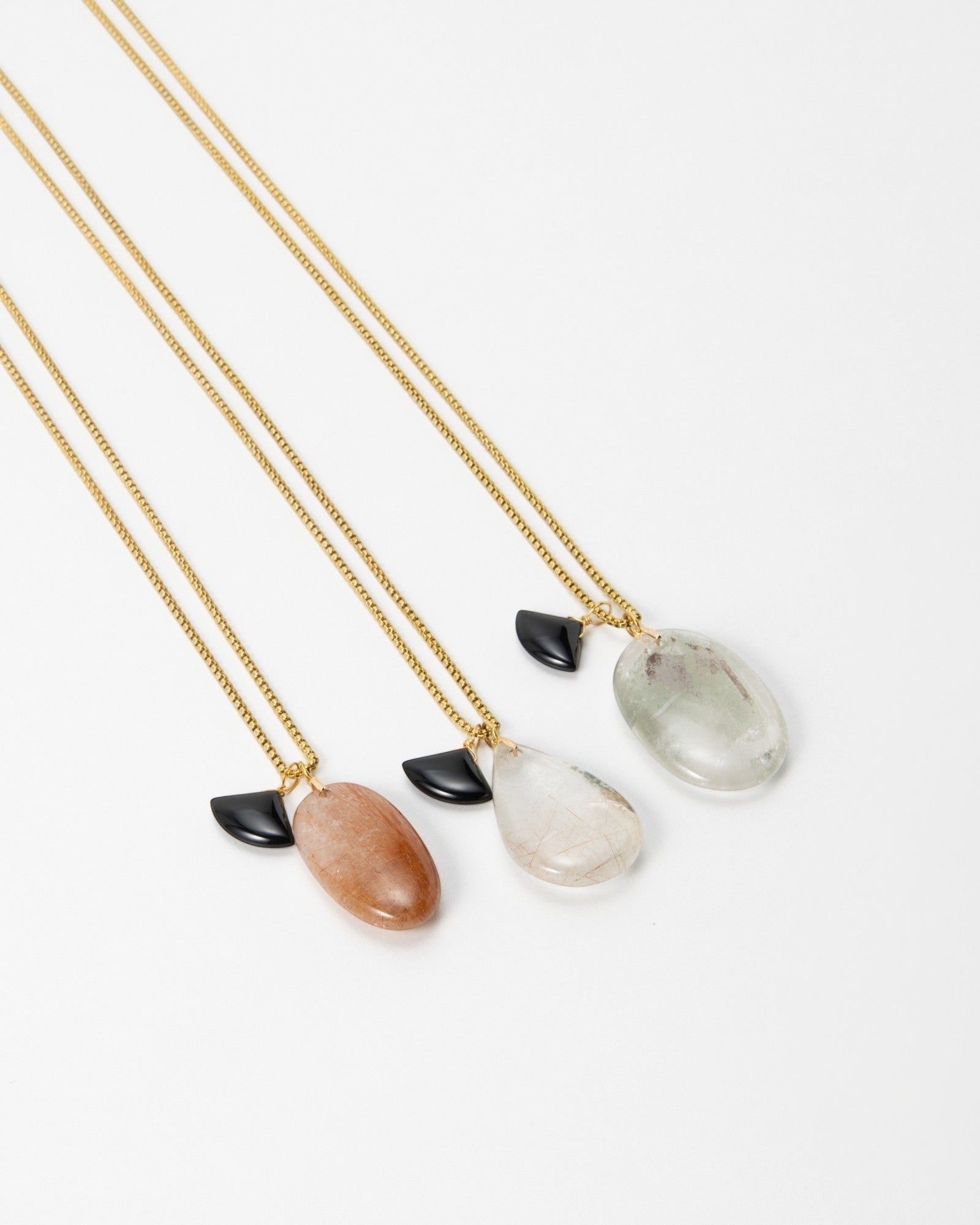 Elsita Jewelry Mist III necklaces featuring gold chains with polished natural stone pendants and black accents.