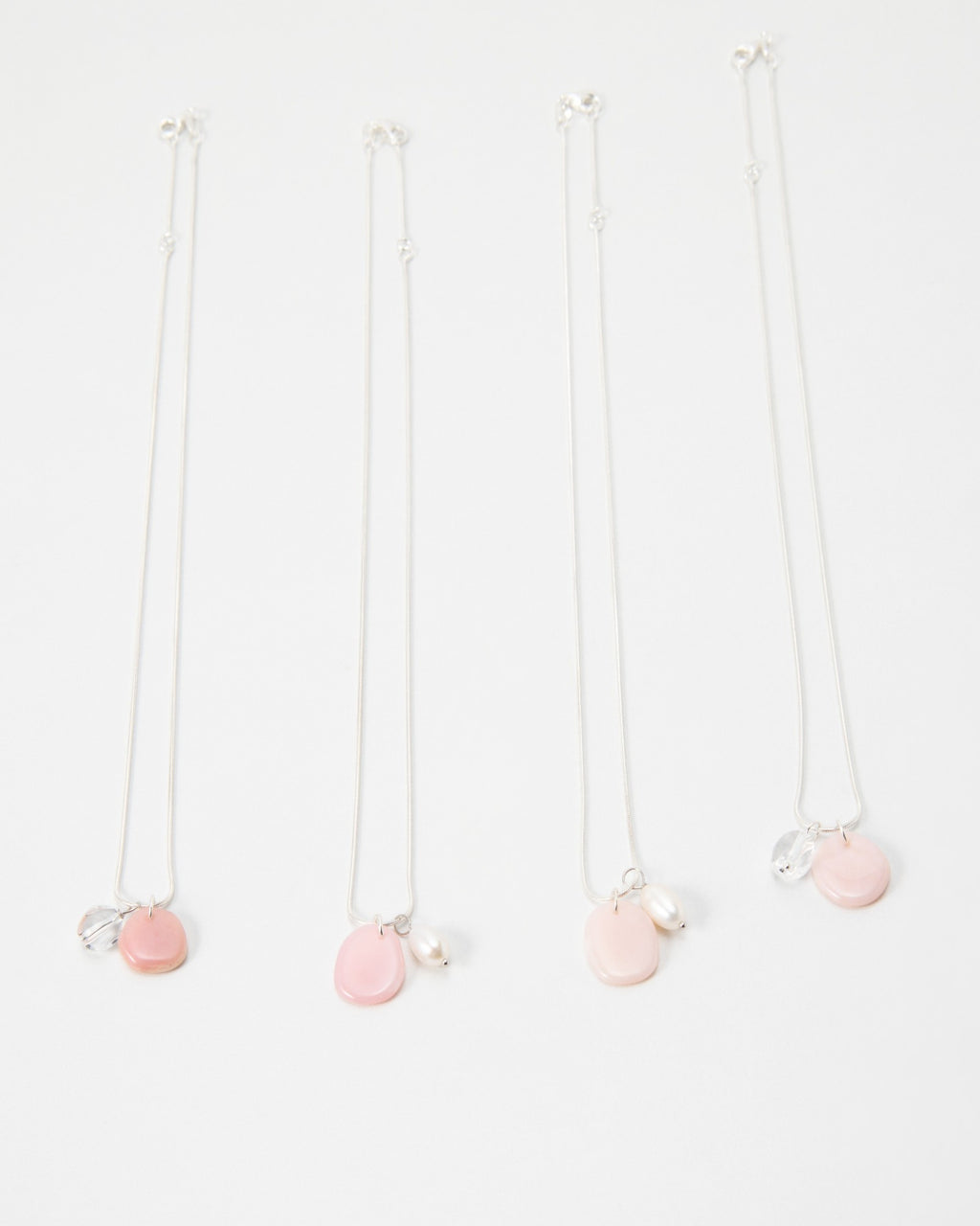 Elsita Jewelry Petal Clear necklaces featuring delicate silver chains with pink petal charms and pearl accents.