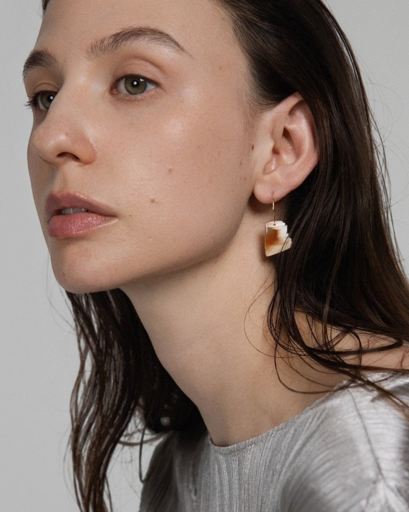 Model wearing Elsita Jewelry Wild 2 raw Indonesian agate slice earrings on 14K gold-filled hoops against grey backdrop