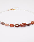 Elsita Jewelry Glow necklace featuring a gradient of red agate, picture jasper, and clear quartz beads on a white background.