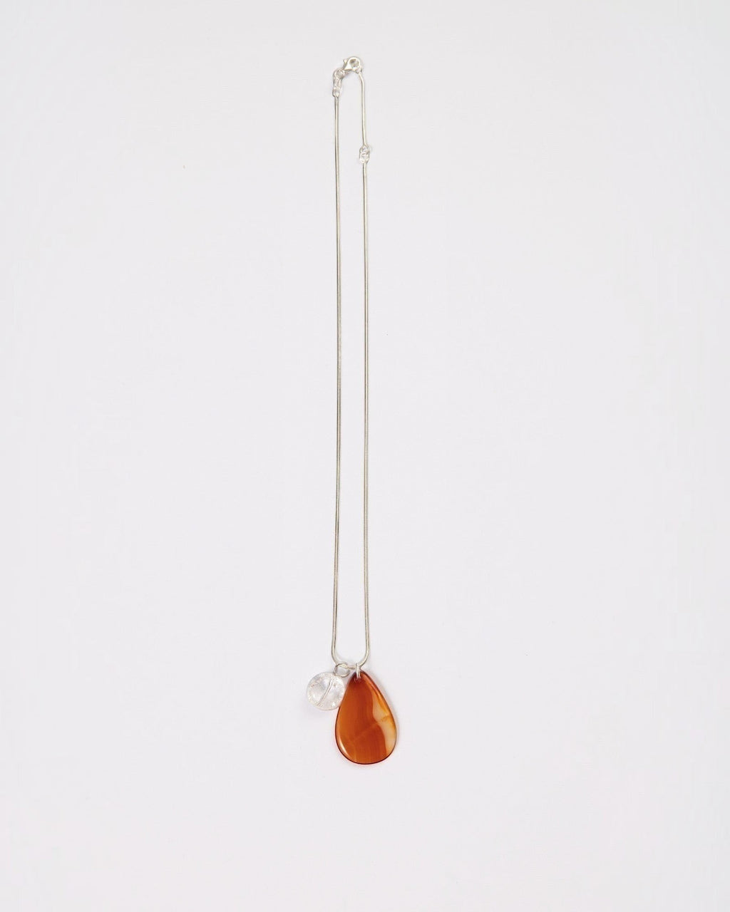 Elsita Jewelry Soda II necklace featuring a teardrop red agate and clear quartz pendant on a sterling silver chain.