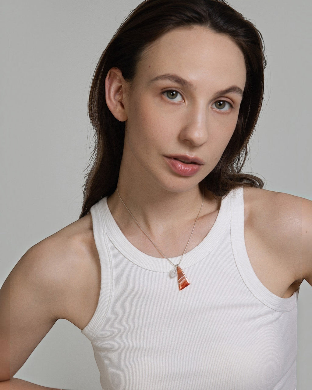 Model wearing Elsita Jewelry Soda III triangular red agate and clear quartz pendant on a sterling silver snake chain.